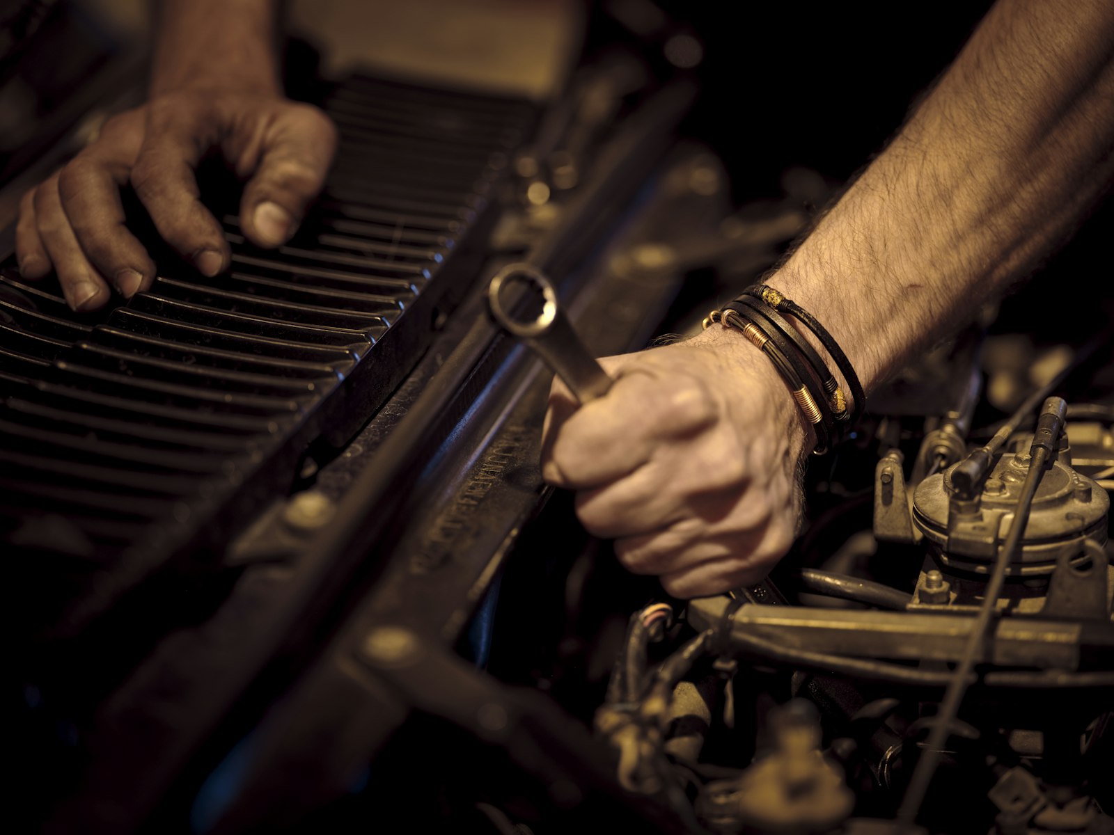 Hands using a wrench on a car engine